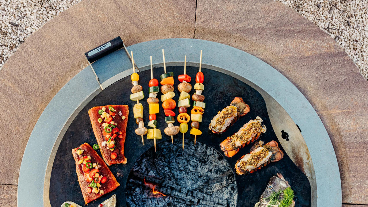 An image of the SearPlate Griddle sitting atop an X series with an Insert Ring, with delicious seafood cooking on the Griddle