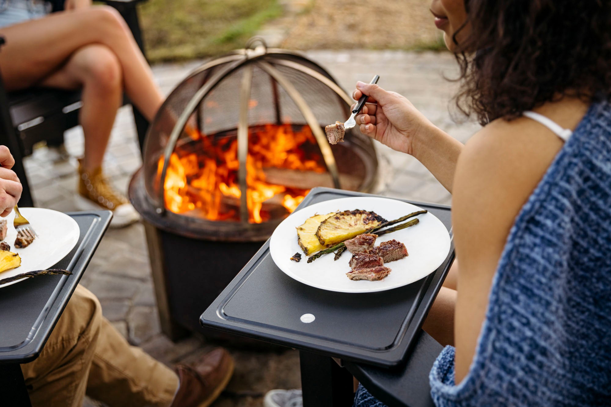 People around breeo smokeless firepit on patio eating food