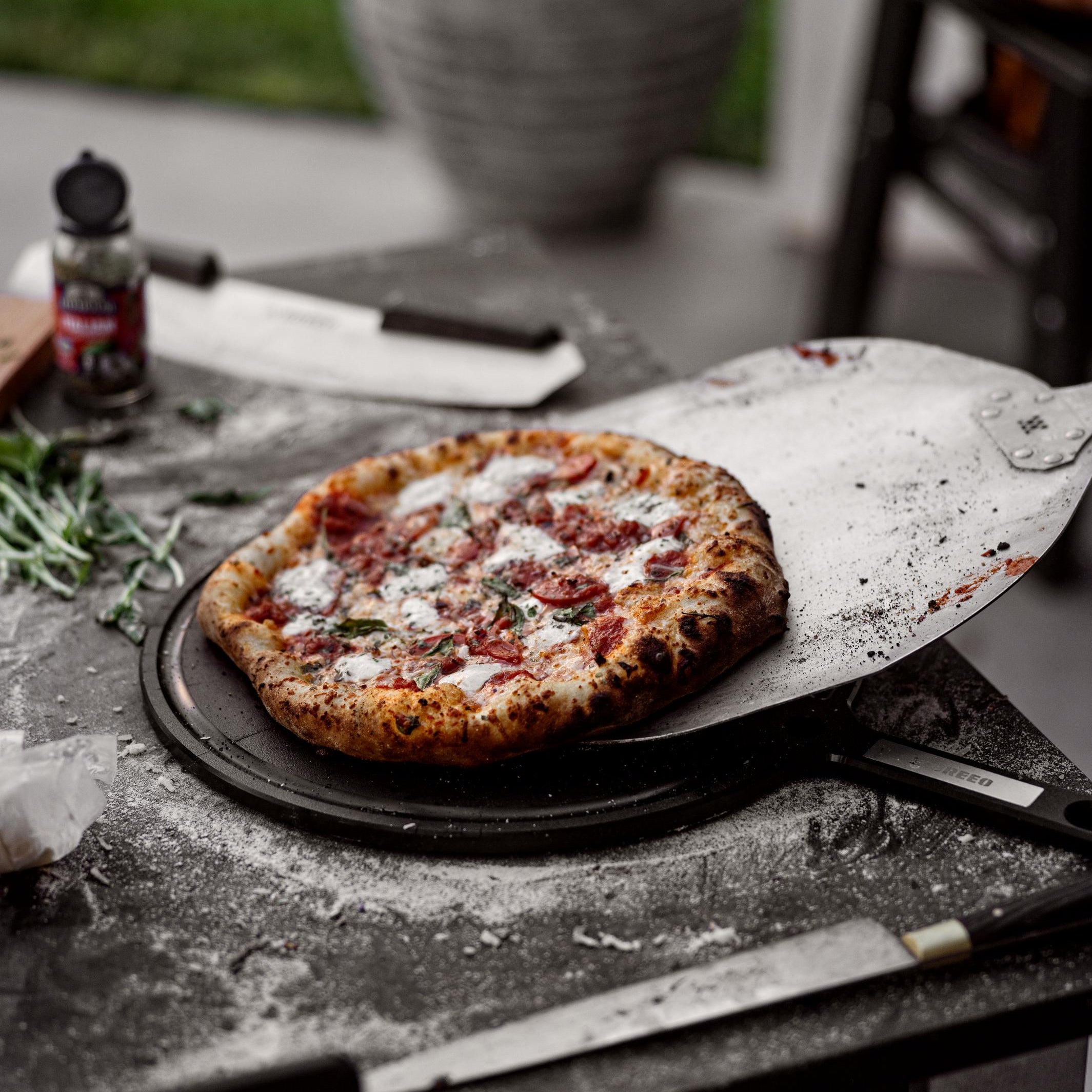 This is an image of pizza being transferred from a Pizza Peel to a Serving Board