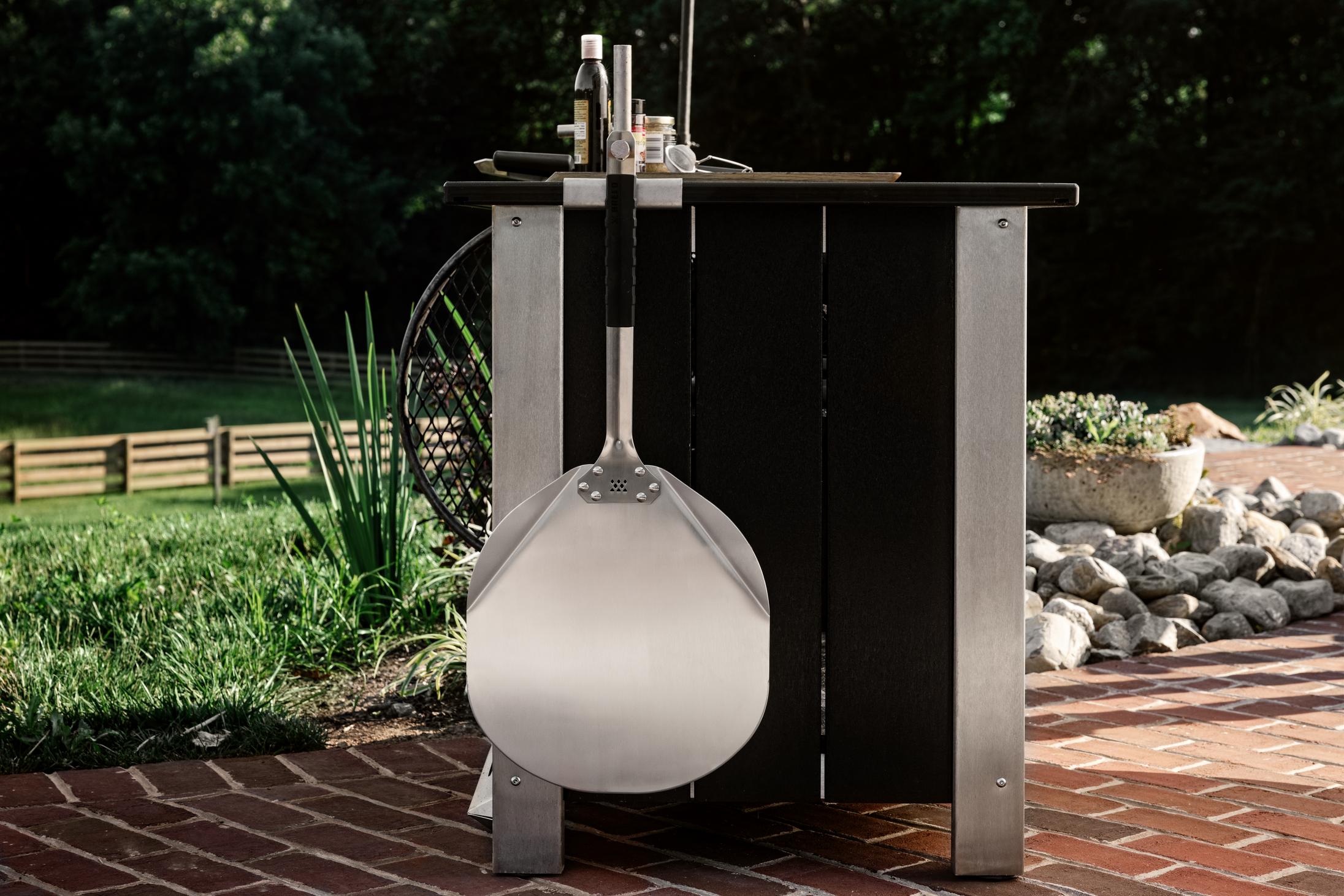 Breeo Pizza Peel hanging from an X Series Table with an Outrig Post