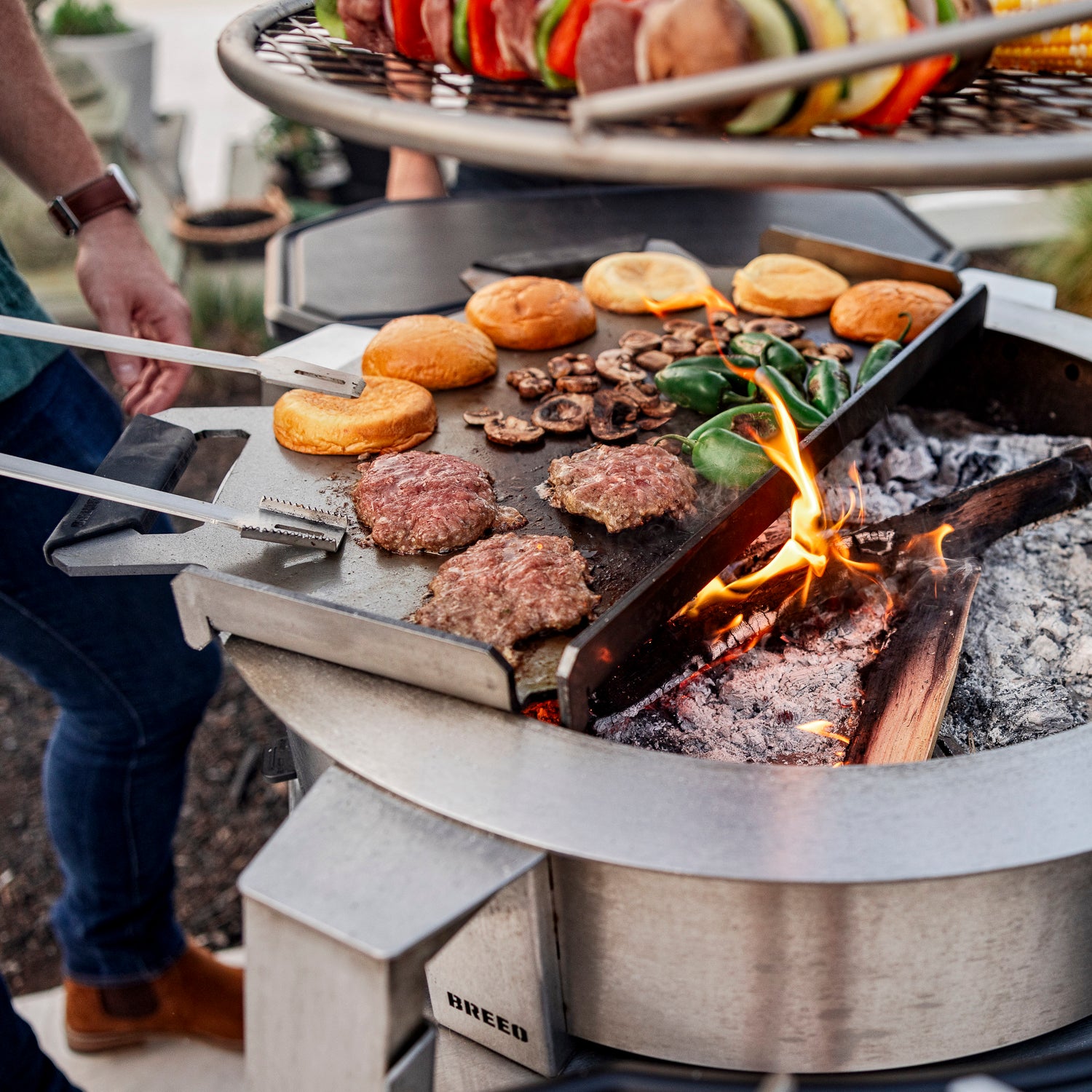 person grilling on breeo firepit sear plate