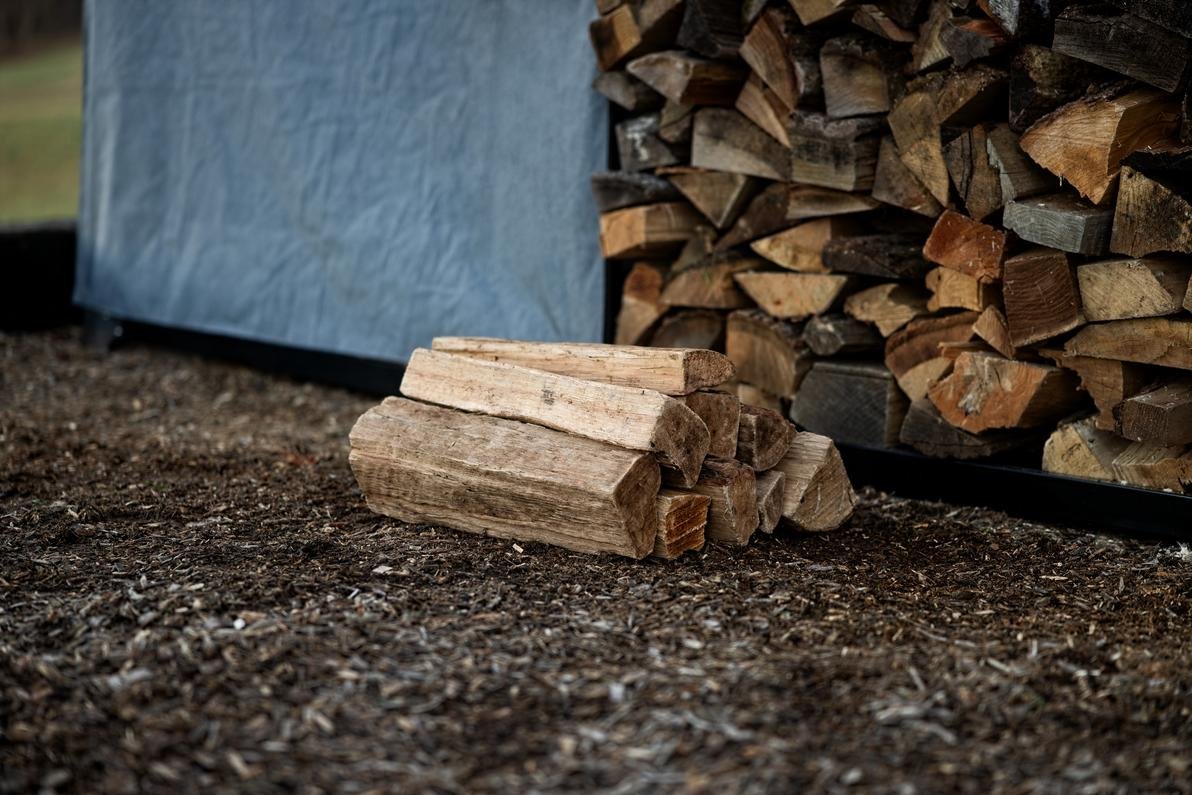 This is an image of a pile of wood in front of the firewood rack and expansion kit.
