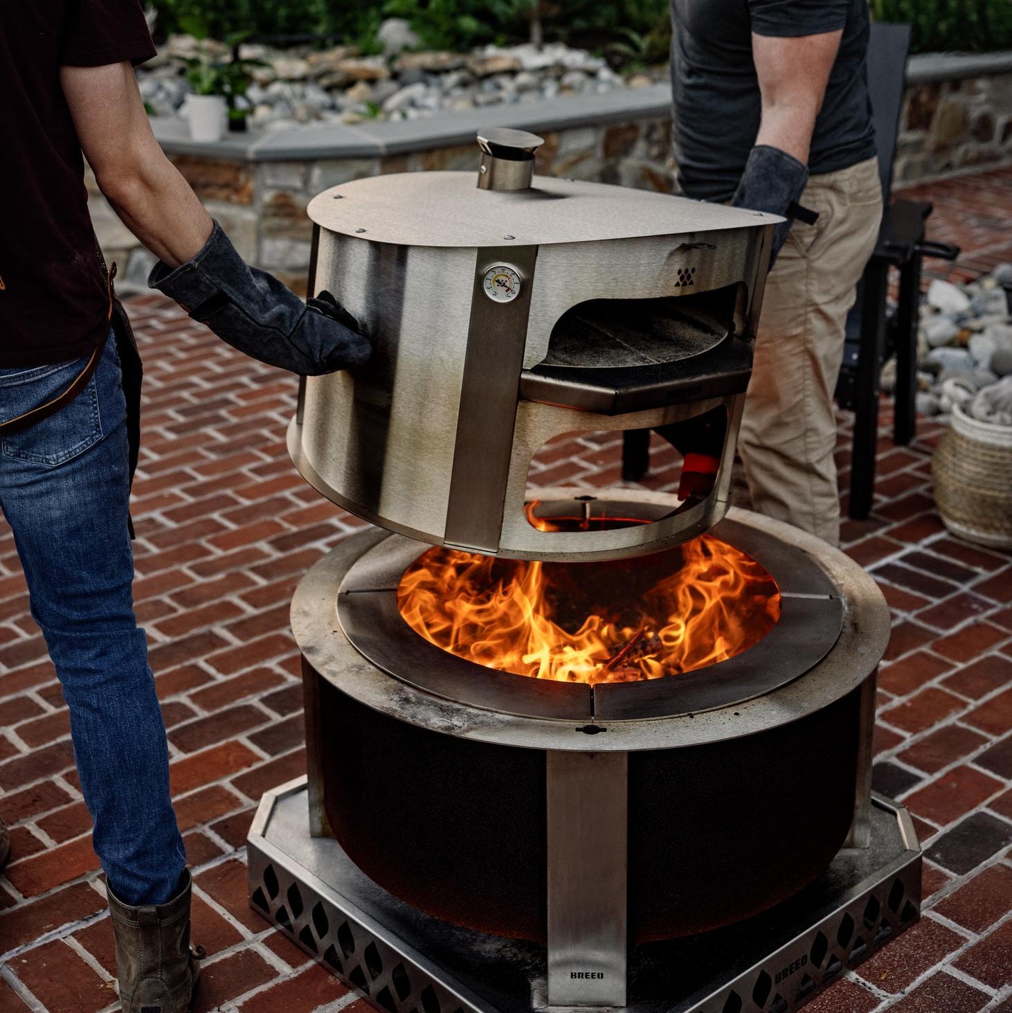 This is an image of two men moving a pizza oven from the firepit