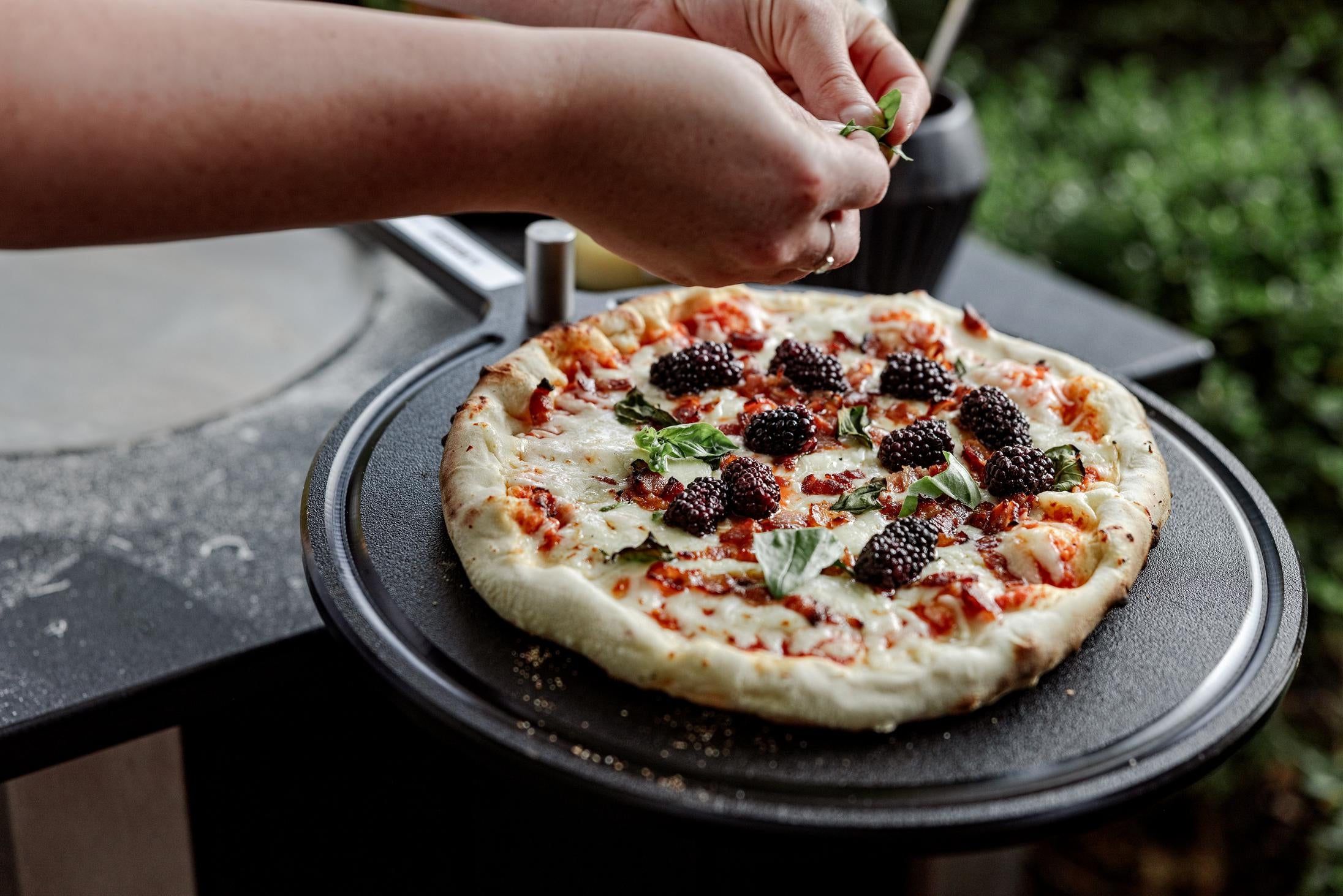 This is an image of fresh pizza sitting on the Breeo Serving Board