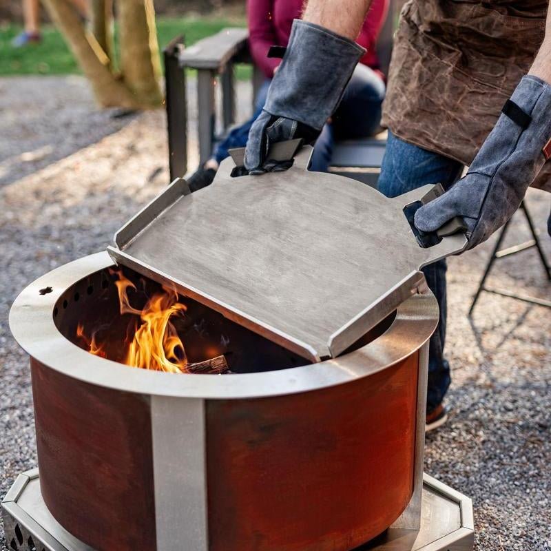 This is an image of a man removing the Flat Top 24 from the firepit
