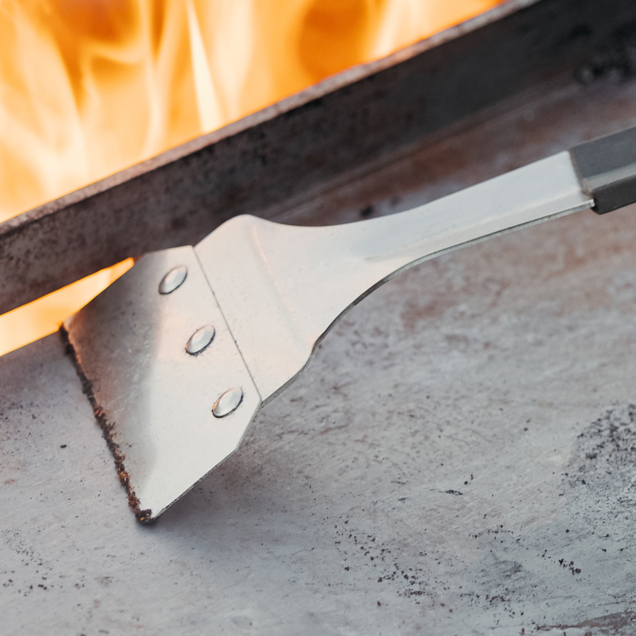 Metal spatula over a flame on a concrete surface