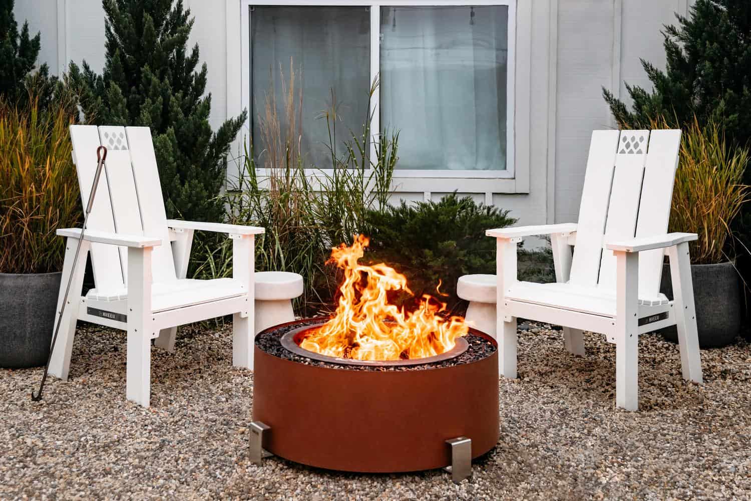 This is an image of  two white X Series Chairs with an Earth Rust Luxeve firepit