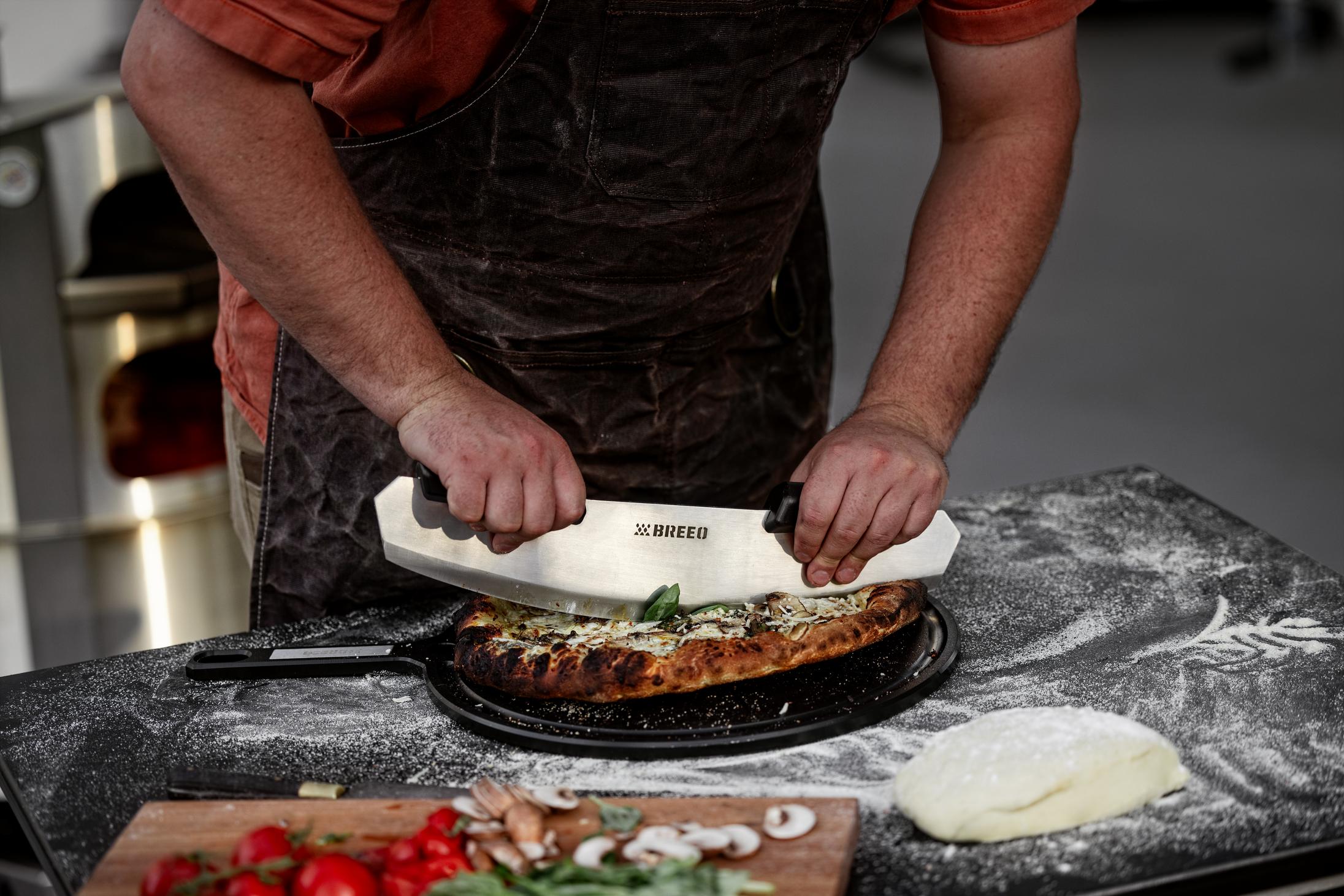 This is an image of someone using the Rocker to slice a pizza on the Serving Board. 