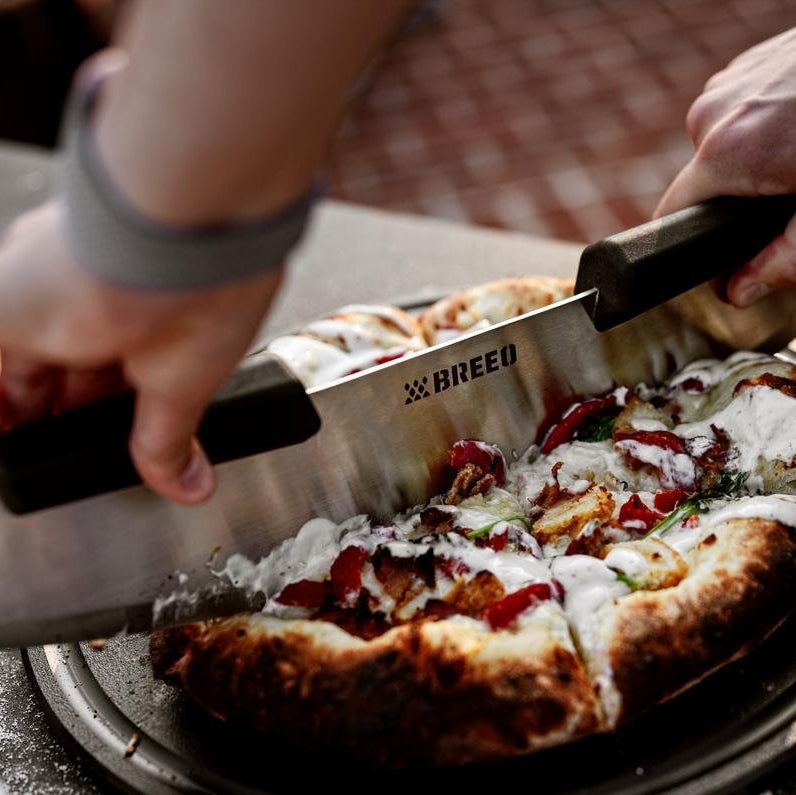This is an image of the Breeo Pizza Rocker used to slice a pizza on the Serving Board