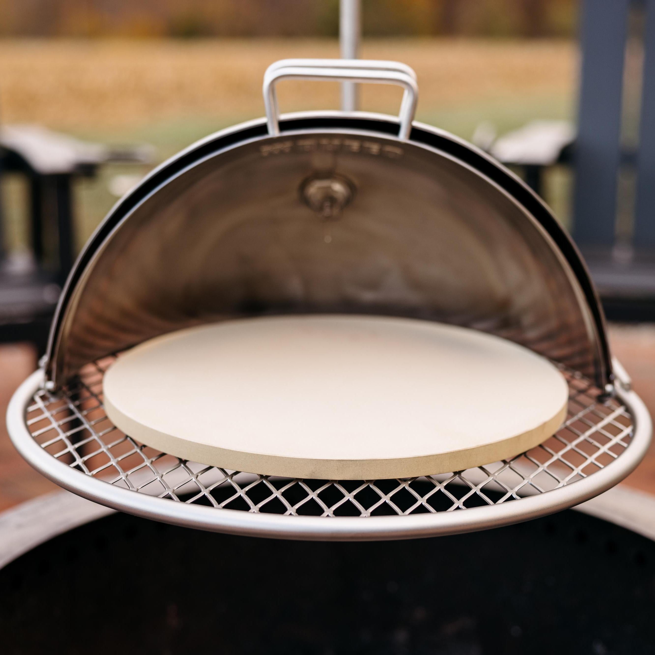 Breeo pizza oven dome with pizza stone placed on Outpost grill grate over live-fire pit, designed for outdoor wood-fired cooking
