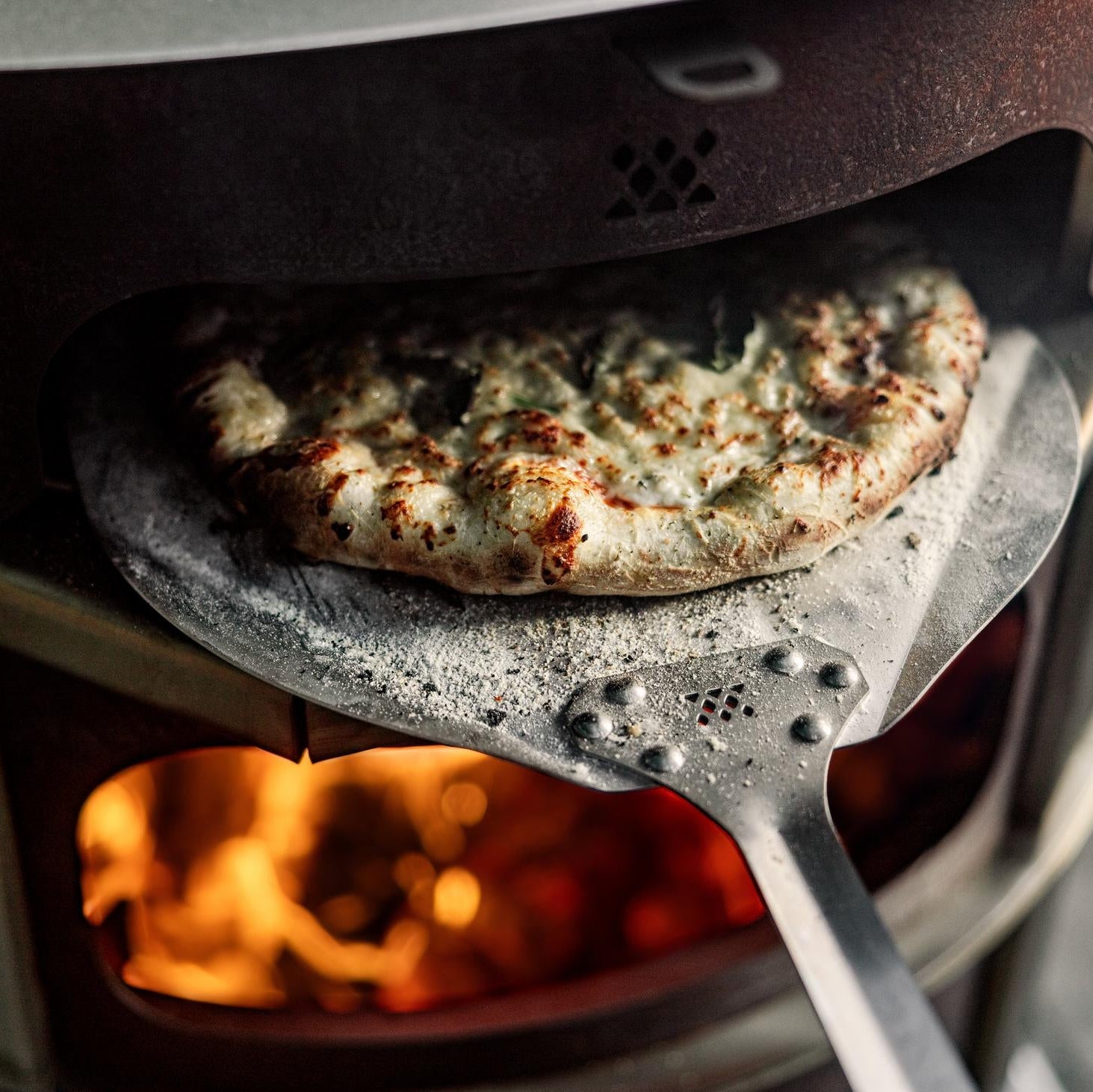 Removing a pizza from the Pizza Oven with a Breeo Pizza Peel