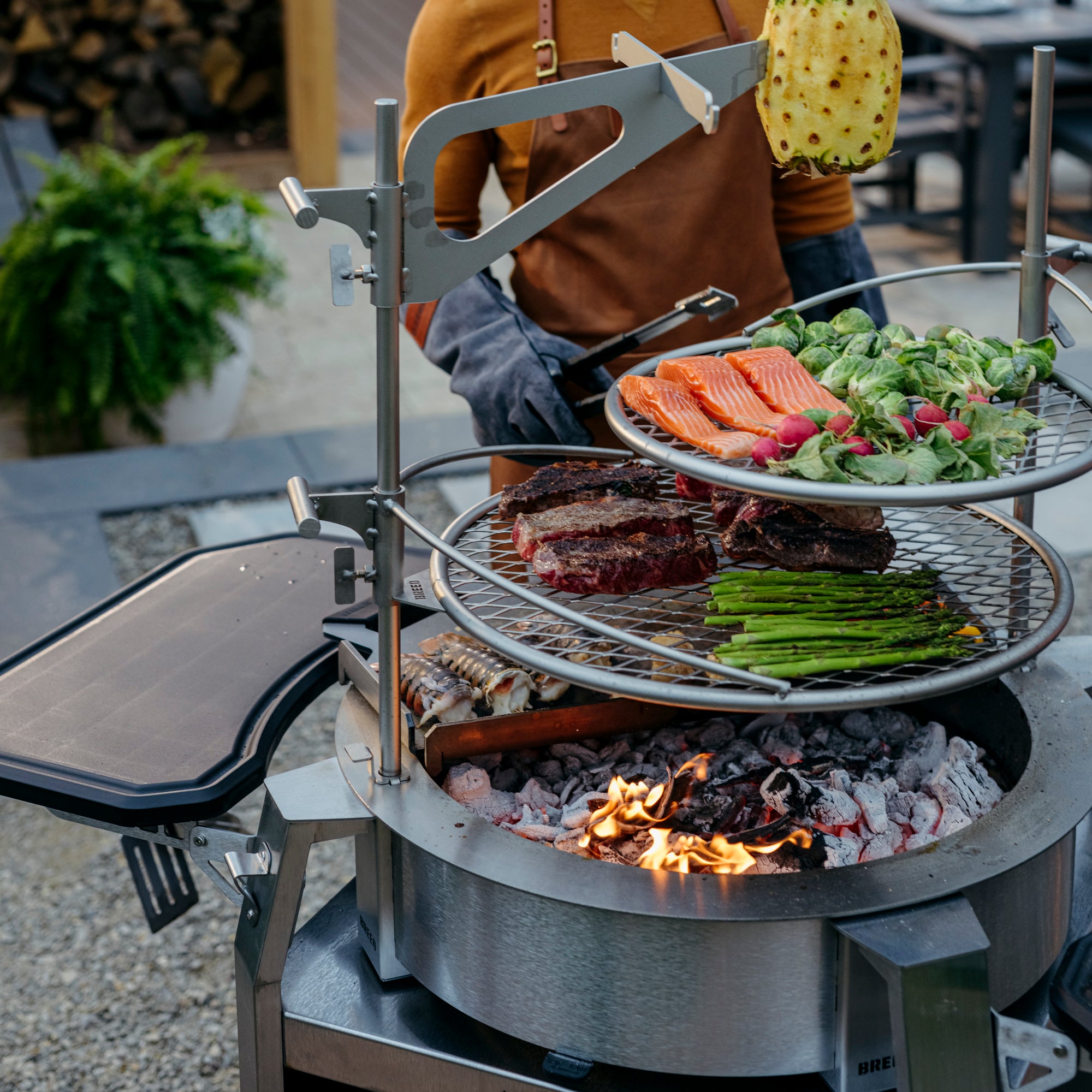 Food cooking over tiered breeo firepit