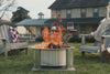 A montage video displaying X series fire pits at gatherings, cooking and grilling, insert bundles burning in stone surrounds, secondary reburn shots, Breeo Lancaster manufacturing shots.