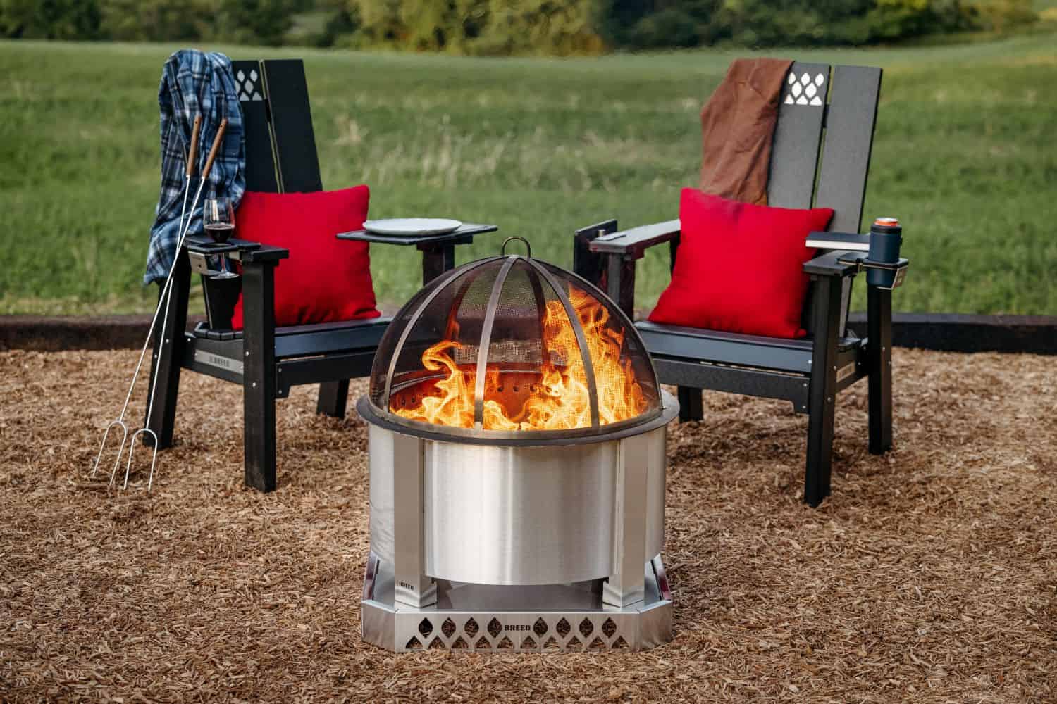 Breeo X Series Chairs set up around a Breeo Firepit with a Base and Spark Screen. 