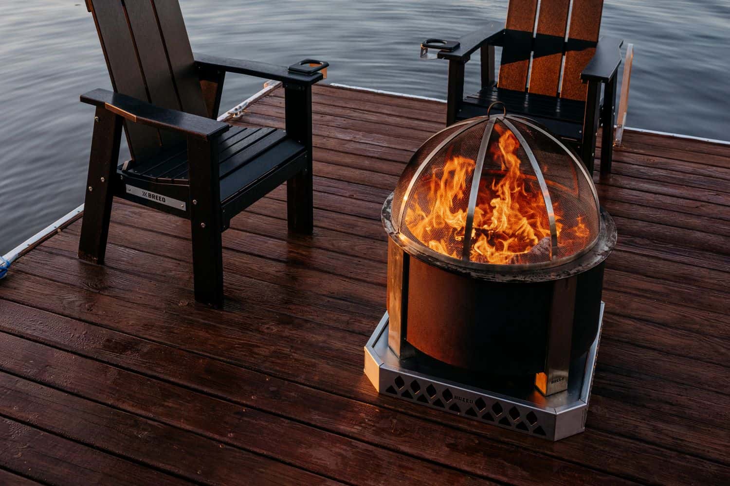 A campfire scene on a dock with a Breeo Base, X Series FIre Pit and two X Series Chairs. 
